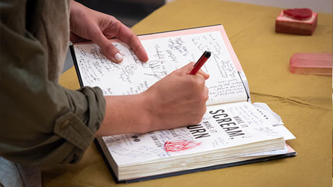 person writing in open book