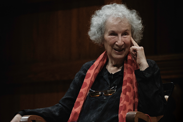 Margaret Atwood, wearing a black top and red scarf with circle details
