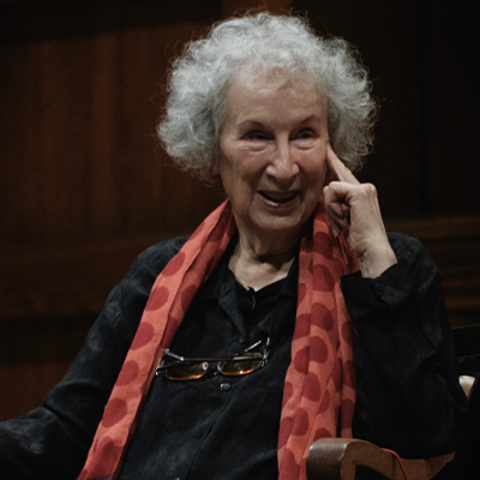 Margaret Atwood, wearing a black top and red scarf with circle details