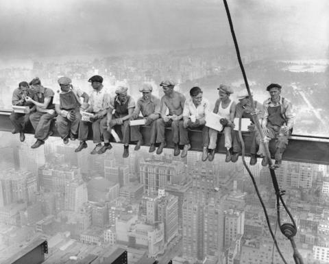 Construction workers eating lunch on steel beam